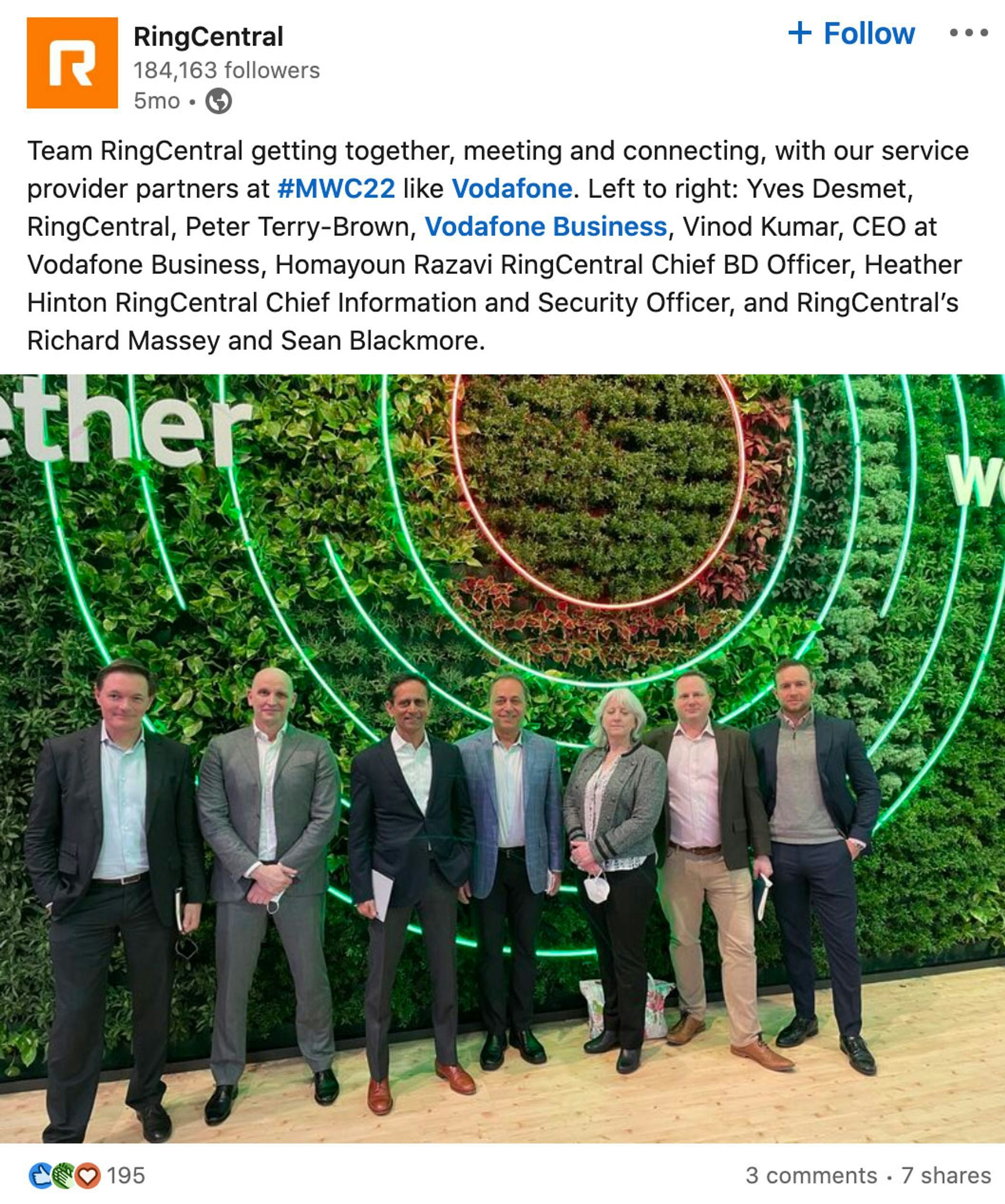 Professionals from RingCentral and Vodafone Business pose together in front of a green, circular logo at #MWC22.