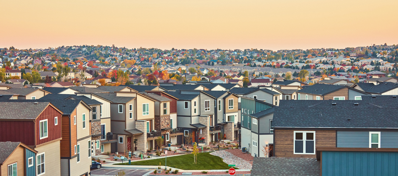 A suburb with rows of colorful houses stretching into the distance during twilight.